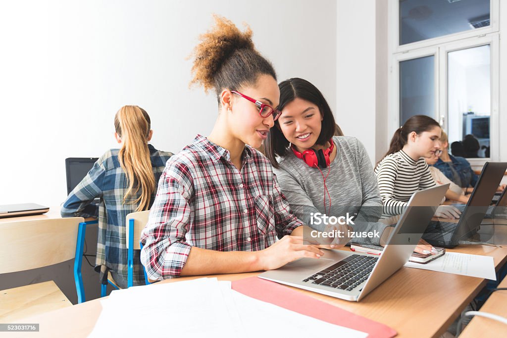 Multi ethnic students learning computer programming, working together Multi ethnic female students coding on laptops in a computer lab. Asian and afro american young women working together. Learning Stock Photo