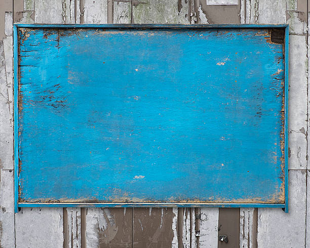 old blue blank weathered wood noticeboard on rough dirty wall background