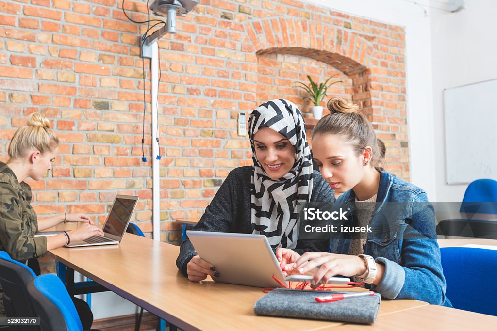 Musilm young woman working on laptop with friend Musilm female student working on laptop with her friend at the university. Achievement Stock Photo