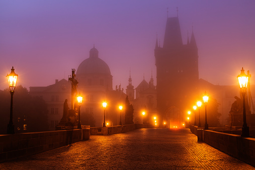 Charles Bridge illuminated by gas lanterns in early, foggy morning, Prague, Czech Republic