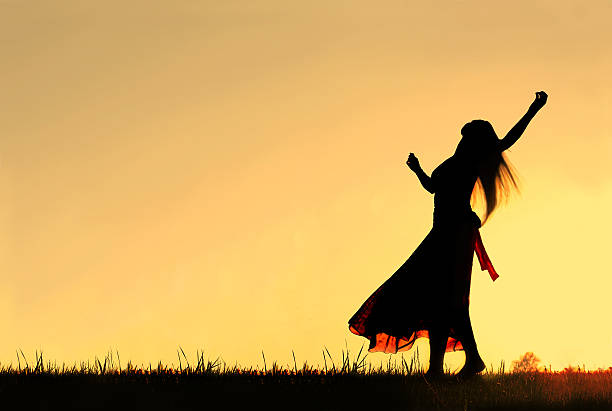 Silhouette of Woman dancing and Rejoicing to God at Sunset A woman wearing a long skirt, with long blonde hair, is dancing and spinning, while silhouetted against the evening sky ballerina shadow stock pictures, royalty-free photos & images