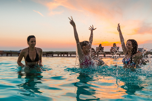 group of friends enjoying the pool party at the sunset.