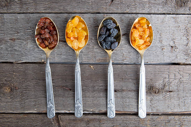 istock Raisins in metal spoons on wooden table 523034566
