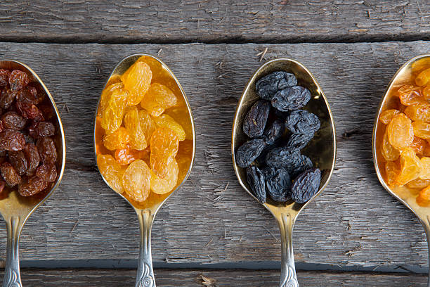 istock raisins in metal spoons on wooden table 523034744