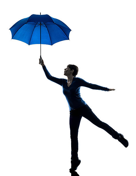 istock woman holding umbrella wind blowing silhouette 523034921