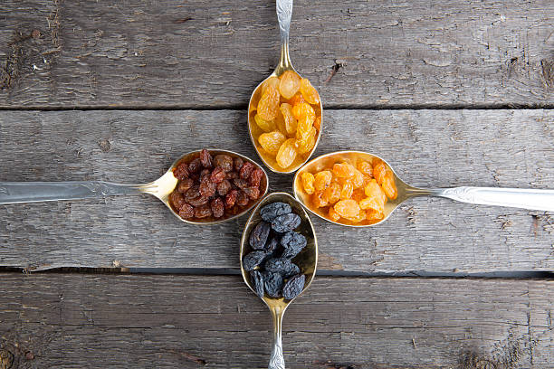 istock Raisins in metal spoons on wooden table 523034940