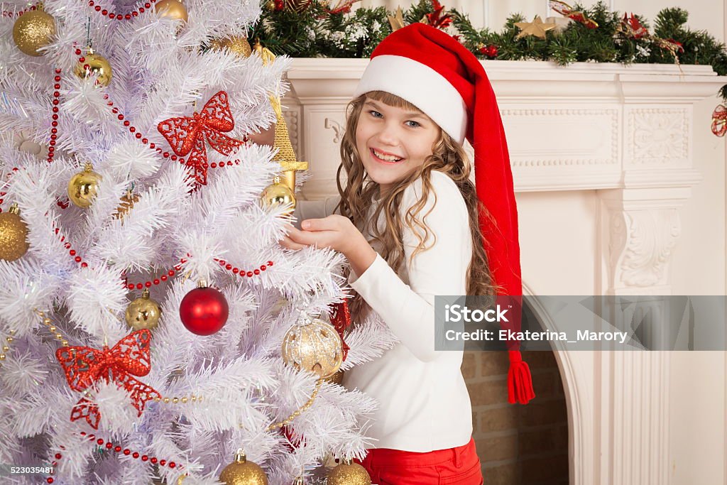 christmas  girl  red cap and pants beautiful  smiling  little blonde girl near the christmas tree with tree toy have red cap and pants Adult Stock Photo