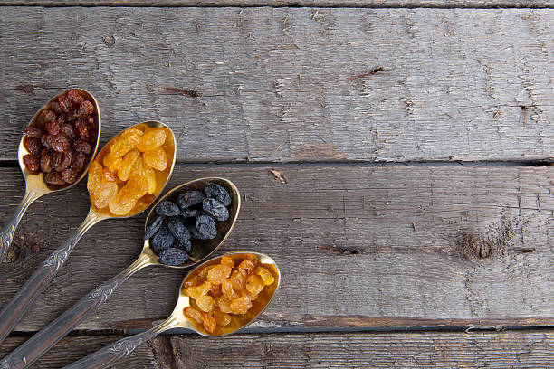 istock raisins in metal spoons on wooden table 523035596