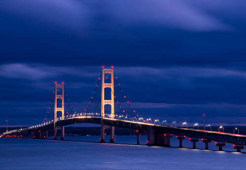 Long exposure shot of Michigan't Mackinac Bridge during a partly cloudy evening.  Shot from the St. Ignace side the clouds move across the image highlighting the bridge.