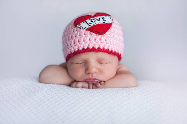 Newborn Baby Girl Wearing a "Love" Hat Portrait of a seven day old sleeping baby girl wearing a crocheted "Love" beanie. Cute shot to use for Valentine's Day. only baby girls stock pictures, royalty-free photos & images