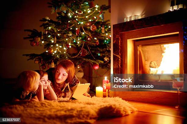 Young Mother And Her Daughters Using A Tablet Pc Stock Photo - Download Image Now - Fire - Natural Phenomenon, Cozy, Fireplace