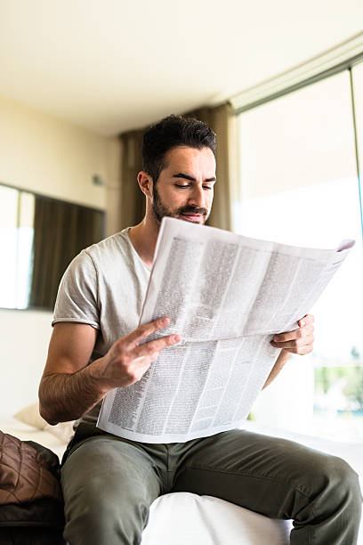 istock man reading the newspaper on bedroom 523038456