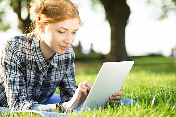 istock woman lying on grass in park and using digital tablet 523041380