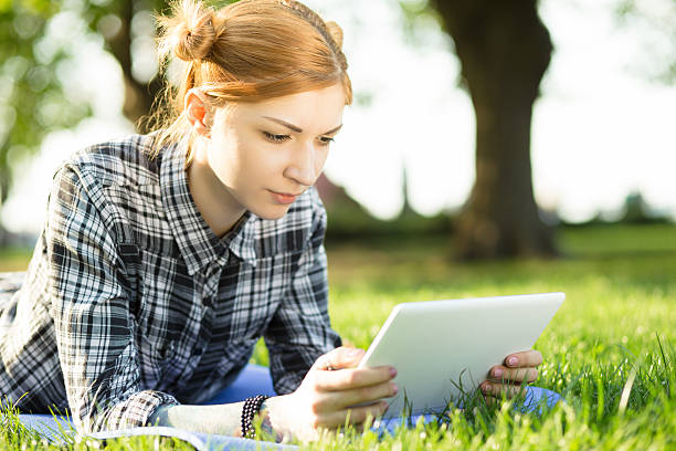 istock woman lying on grass in park and using digital tablet 523041474