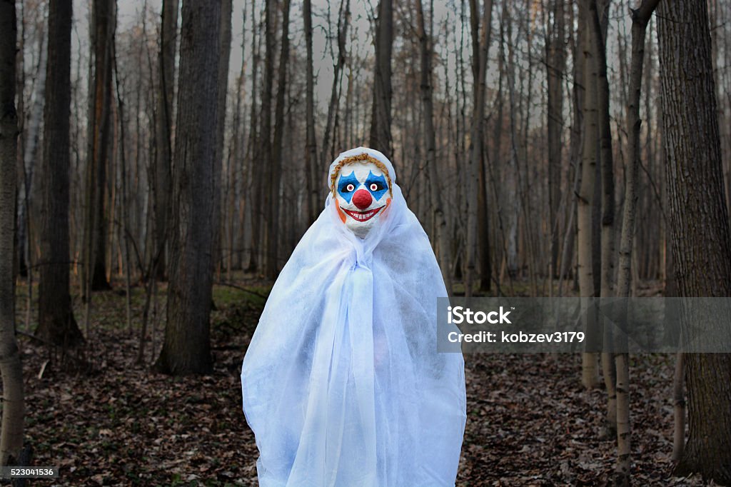 Mal clown dans une forêt sombre dans un voile blanc - Photo de Clown libre de droits