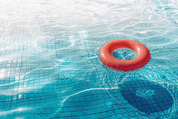 istock orange swim ring floating  in blue swimming pool 523044090
