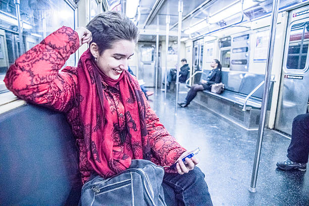 Young 19-years-old girl riding the train, and usung the smartphone in the subway car. New Yourk City subway, USA.