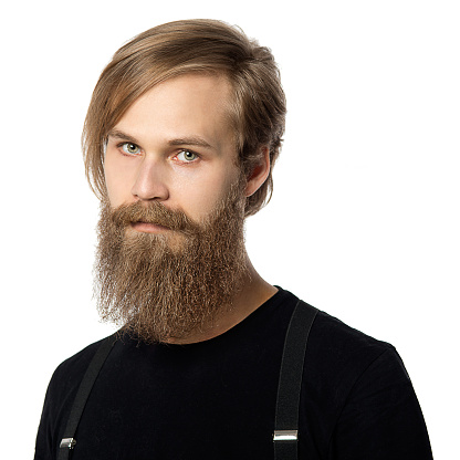 the attractive man the blonde with long hair of the European appearance with a beard in a black t-shirt and black trousers on a white background