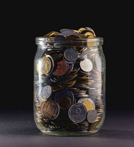 Jar of Money Isolated on a black Background Jar of Money Isolated on a black Background. canadian coin stock pictures, royalty-free photos & images