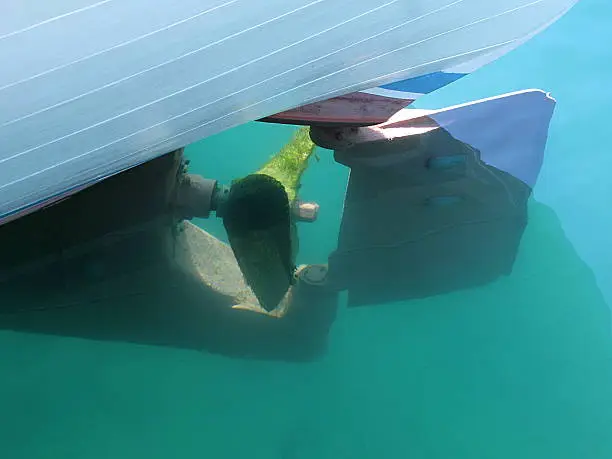 Boat propeller and rudder below the water surface.