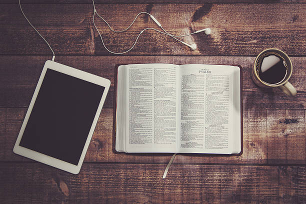 Bible with tablet and coffee in a wooded table..