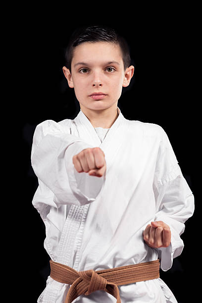 istock Karate boy in white kimono fighting isolated on black  background 523056328