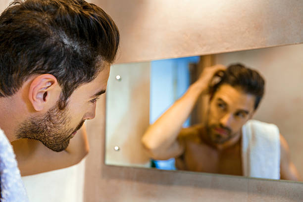 istock Man examining hair in mirror 523058910