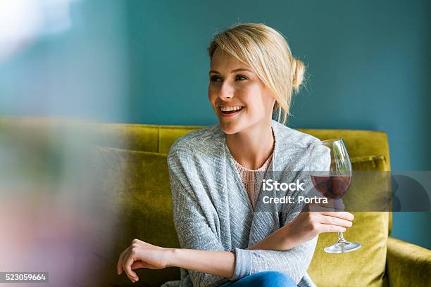 Happy Woman Holding Glass Of Red Wine On Sofa Stock Photo - Download Image Now - Women, Drinking, Alcohol - Drink