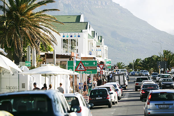 Camps Bay, South Africa - October 23, 2014: The promenade of Camps Bay at the atlantic ocean close to Cape Town in South Africa. In the back you can see mountains of the famous Twelve apostels. In the front people are strolling down the promenade which is famous for its restaurants. 