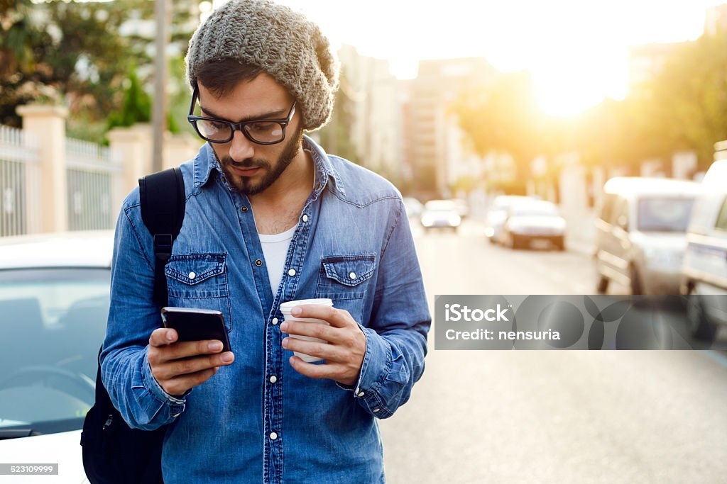 Moderno giovane uomo con telefono cellulare in strada. - Foto stock royalty-free di Ambientazione esterna