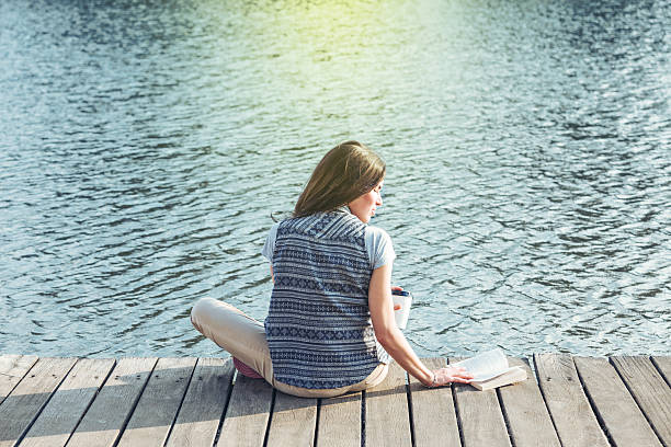istock handsome girl with reading a book on a pier 523111171
