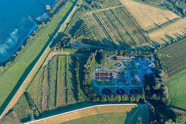 Sewage Treatment Plant with Rhine River Sewage Treatment Plant with Rhine River - Sedimentation Tanks for biological cleaning of industrial and domestic sewage by using microorganisms - Rheinberg, Northrhine-Westfalia, Germany, Europe rheinberg illumination stock pictures, royalty-free photos & images