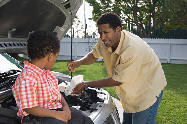 istock Boy assisting father checking oil level in car 523136107