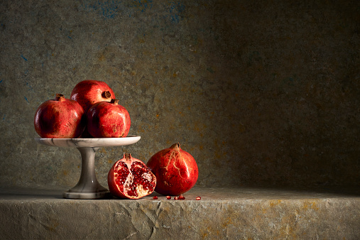 A raised tray with some pomegranates on a multicolor sponged  background.