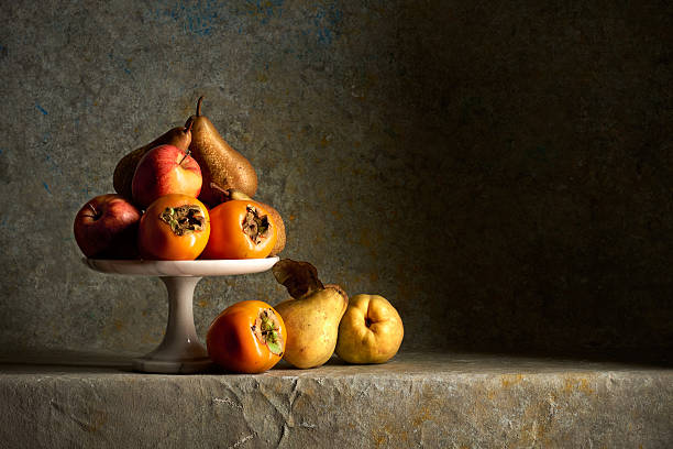 A raised tray with some autumn fruits,apples,pears,persimmons and quinces on a multicolor sponged background.