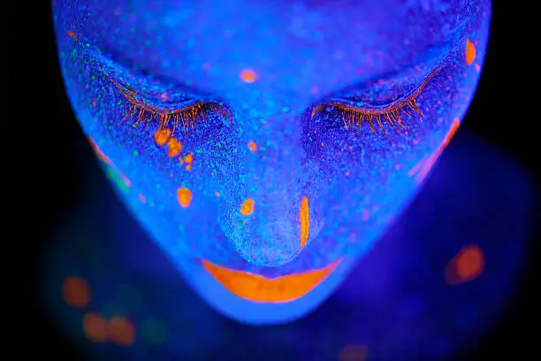 Shot of a young  woman posing with neon paint on her face