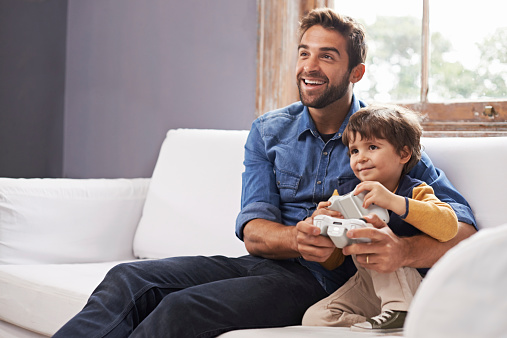 A handsome father and his cute son playing a video game together