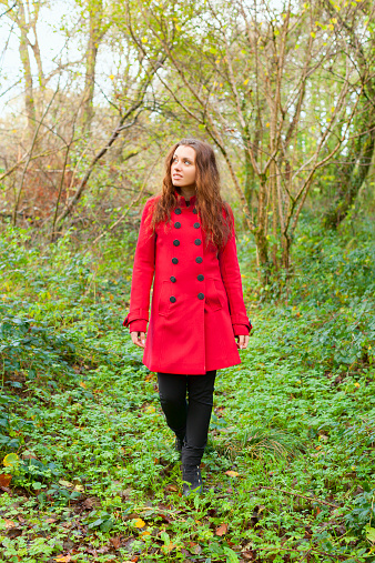 Cute brunette out walking in the countryside in Autumn along an overgrown path.