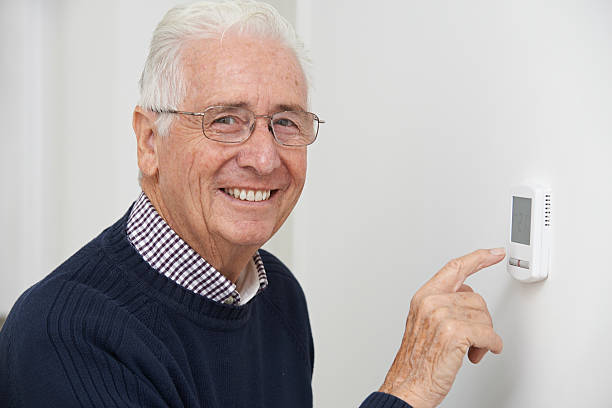 istock Smiling Senior Man Adjusting Central Heating Thermostat 523145157
