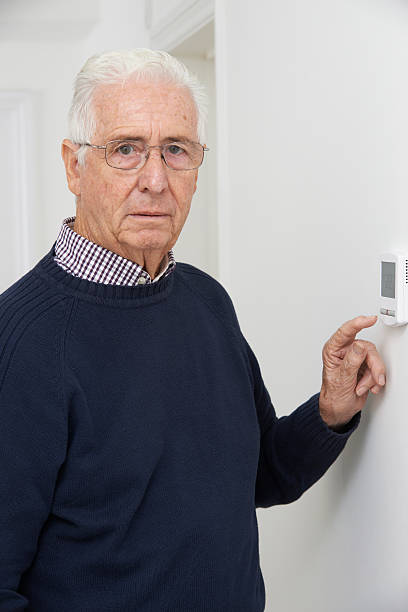istock Worried Senior Man Turning Down Central Heating Thermostat 523145341