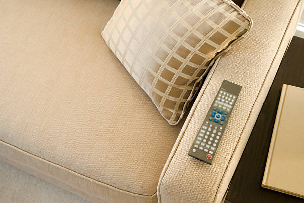 A TV remote control on the armrest of sofa
