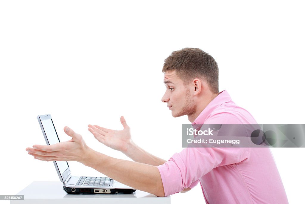 Problems with a laptop computer. A young handsome man sitting at the table and working on his laptop. Something has gone wrong and he expresses deep pertrubation. Adult Stock Photo