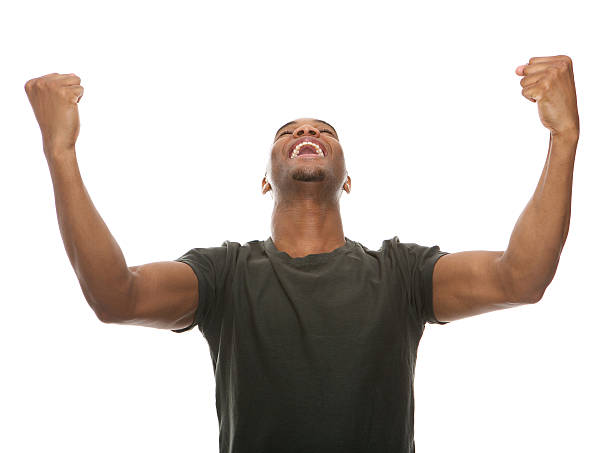 Cheerful young man shouting with arms raised in success Portrait of a cheerful young man shouting with arms raised in success punching the air stock pictures, royalty-free photos & images