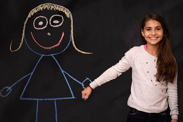Portrait of a little girl standing in front of a chalkboard drawing