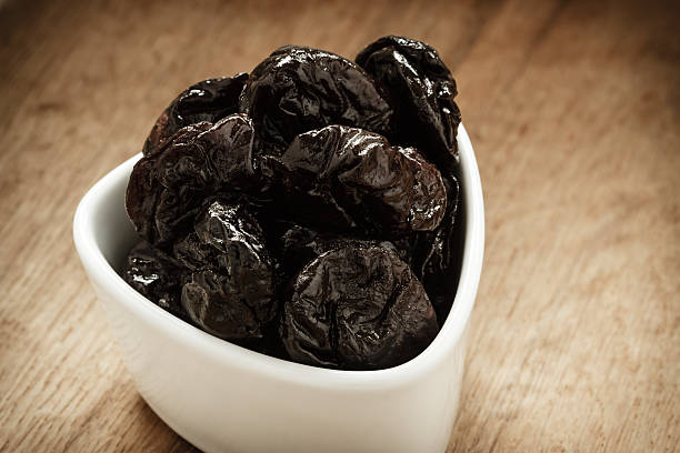 istock dried plums prunes in white bowl on wooden table 523159036