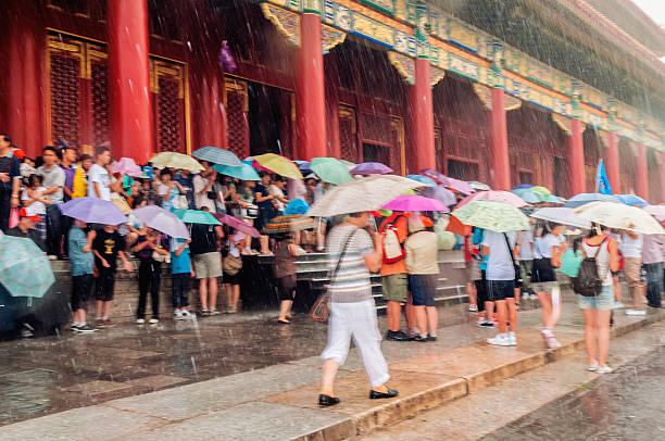 Tourists in Forbidden City, storm, Beijing, China Beijing, China - August 7, 2009: Lots of Chinese and foreign tourists in Forbidden. The stone floor in front is wet and reflects people and buildings, storm. The Forbidden City was the Chinese imperial palace from the Ming Dynasty to the end of the Qing Dynasty. It is located in the middle of Beijing, China, and now houses the Palace Museum. For almost five hundred years, it served as the home of emperors and their households, as well as the ceremonial and political centre of Chinese government. Built in 1406 to 1420, the complex consists of 980 buildings with 8,707 bays of rooms. Nikon D300. Copy space. forbidden city beijing architecture chinese ethnicity stock pictures, royalty-free photos & images