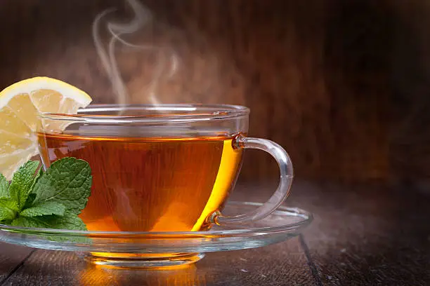 Cup of tea with mint and lemon on a wooden background