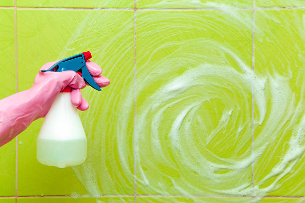 istock Hand in protective glove holding spray bottle to clean tiles 523174252