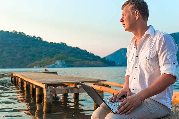 istock man in white shirt with laptop on the pier 523178979