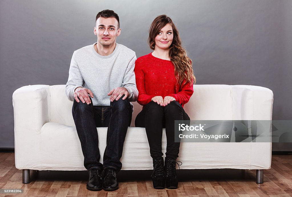 Shy woman and man sitting on sofa. First date. Shy woman and man sitting on sofa couch next to each other. First date. Attractive girl and handsome guy meeting dating and trying to talk. Embarrassment Stock Photo